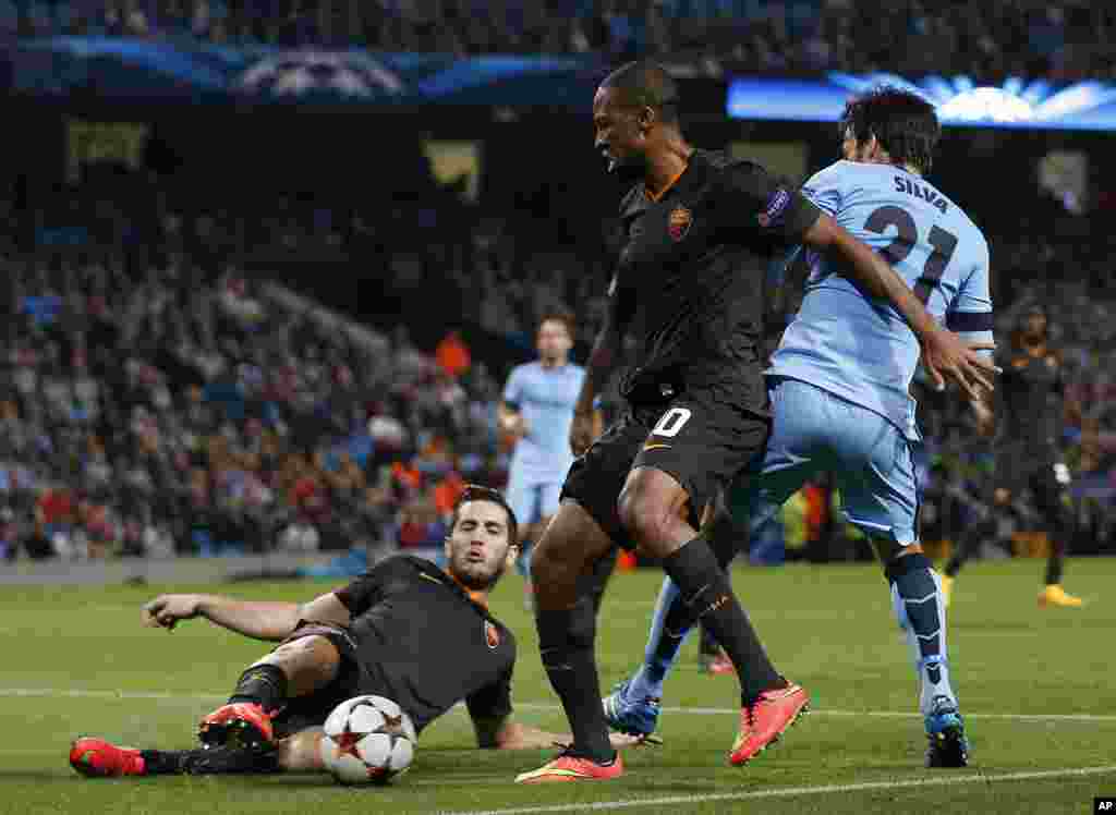 Seydou Keita et son coéquipier Konstantinos Manolas de Roma, à gauche, en lutte pour le ballon contre David Silva de Manchester City lors d'un match de la Champions League entre Manchester City et Roma au Stade Etihad, Manchester, en Angleterre, mardi 30 septembre 2014.