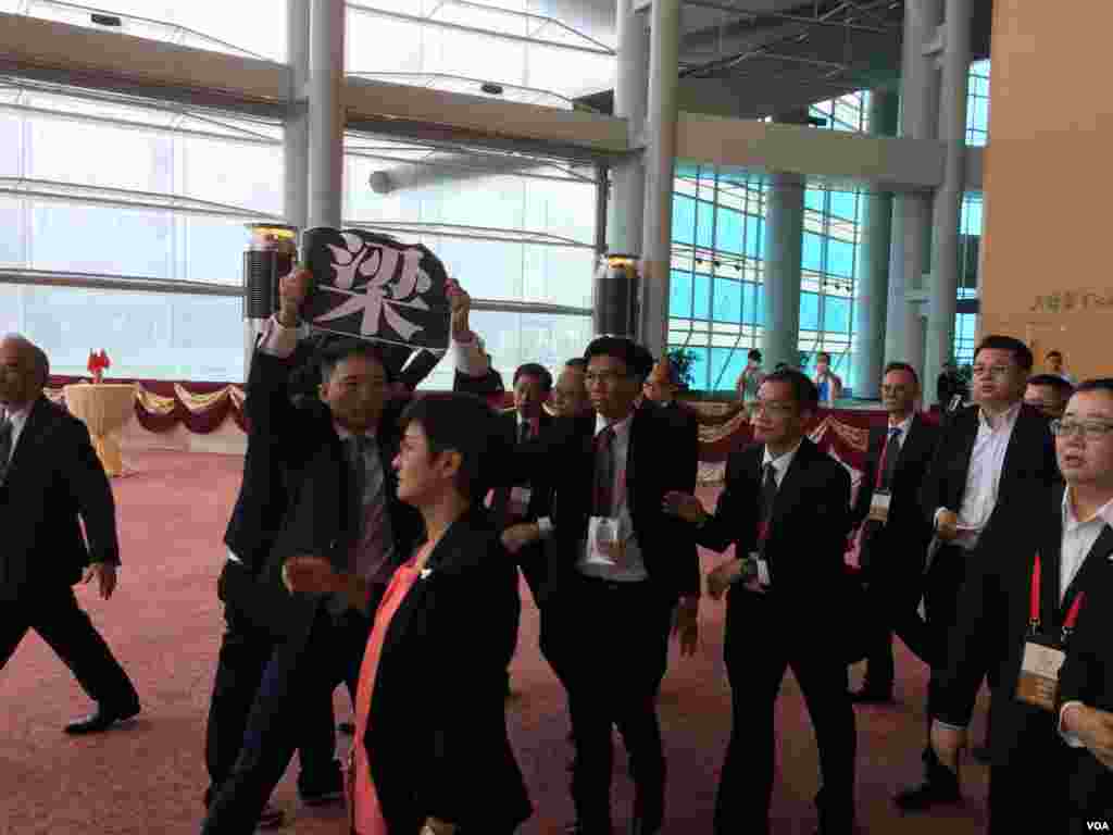 香港特区政府星期六在会展中心举办国庆67周年大型酒会。在特首梁振英开始致辞后,参加酒会的多位候任民主党立法会议员,举起反梁标牌和单张,高喊梁振英下台的口号,被大批保安人员带出会场。(美国之音海彦拍摄)