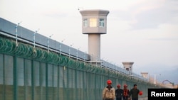 FILE PHOTO: Workers walk by the perimeter fence of what is officially known as a vocational skills education center in Dabancheng in Xinjiang Uighur Autonomous Region, China,Sept. 4, 2018. 