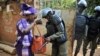 Un policier fouille le sac d'une femme devant un bureau de vote à Bamako, 20 novembre 2016.