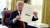 FILE - President Donald Trump displays the $1.5 trillion tax overhaul package he had just signed, Dec. 22, 2017.