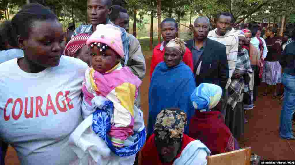 Watoto wakifuatana na wazazi wao pamoja na wazee wasubiri kupiga kura mjini Gatundu