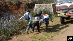 In this Feb. 17, 2015, photo provided by the Eleven Media Group, Myanmar red-cross members carry an injured victim during a clash between government troops and Kokang rebels in Kokang, northeastern Shan State, more than 800 kilometers (500 miles) northeast of Yangon, Myanmar.