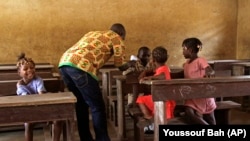 Un travailleur de la santé prend la température d'écoliers lors de l’épidémie d’Ebola dans une salle de classe, à Conakry, en Guinée, le 19 janvier 2015. 