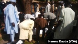 Des hommes réunis autour des corps des défunts, morts pendant l'attentat suicide, à Maiduguri, au Nigeria, le 12 juillet 2017.
