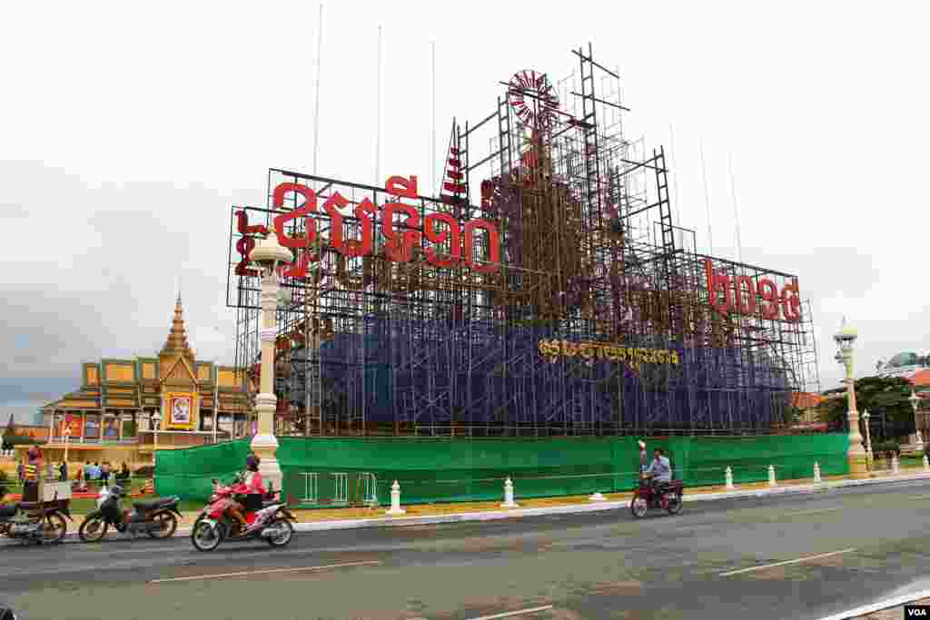 ការរៀបចំតុបតែងលម្អនៅមុខព្រះបរមរាជវាំងក្នុងរាជធានីភ្នំពេញ ដើម្បីអបអរថ្វាយព្រះពរខួបទី១០នៃព្រះរាជពិធីគ្រងរាជសម្បត្តិរបស់ព្រះបាទសម្ដេចព្រះបរមនាថ នរោត្តម សីហមុនី នៅថ្ងៃទី ២៥ ខែតុលា ឆ្នាំ២០១៤។ (នូវ ពៅលក្ខិណាVOA)
