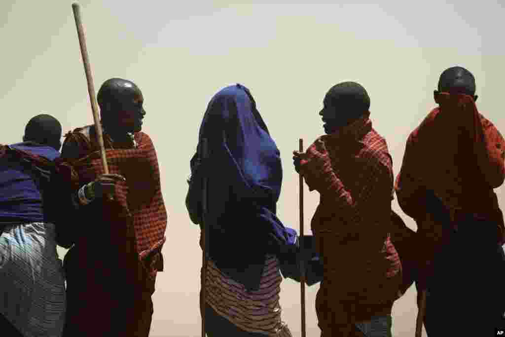 Des membres de la tribu Maasai se couvrent le visage se protégeant contre une tempête de sable dans un village à la périphérie de Serengeti, dans le nord de la Tanzanie. Les Massaïs sont un peuple semi-nomades qui migrent d'un endroit à l'autre.