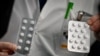FILE - Medical staff at the IHU Mediterranee Infection Institute in Marseille show tablets containing chloroquine and tablets containing hydroxychloroquine, Feb. 26, 2020.