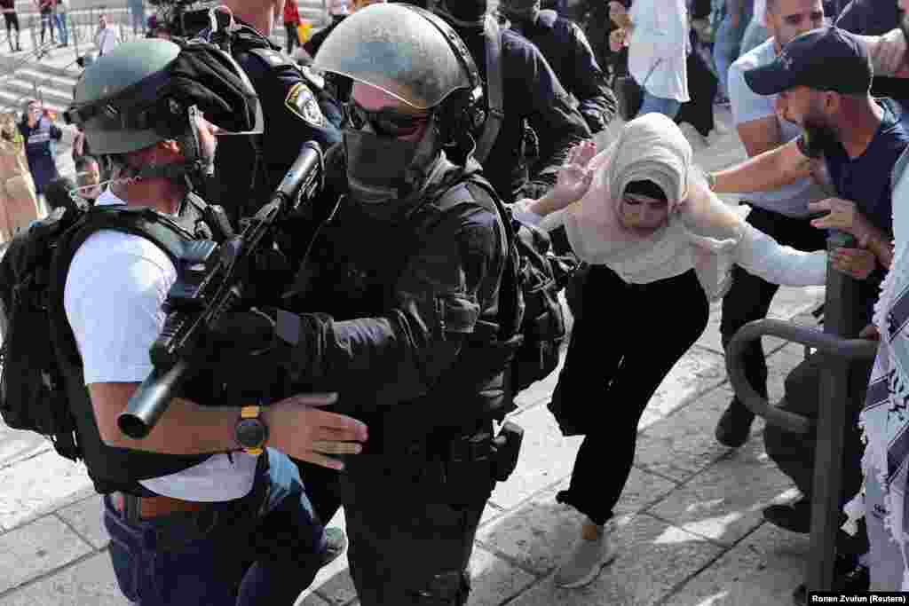 Mwanamke wa Kipalestina akiwa karibu na vikosi vya usalama vya Israeli wakati wa machafuko kati ya Waisraeli na Wapalestina huku Israeli ikiadhimisha Siku ya Jerusalem, katika eneo la Damascus Gate nje ya mji wa Old City, Jerusalem, Mei 10, 2021. REUTERS/Ronen Zvulun