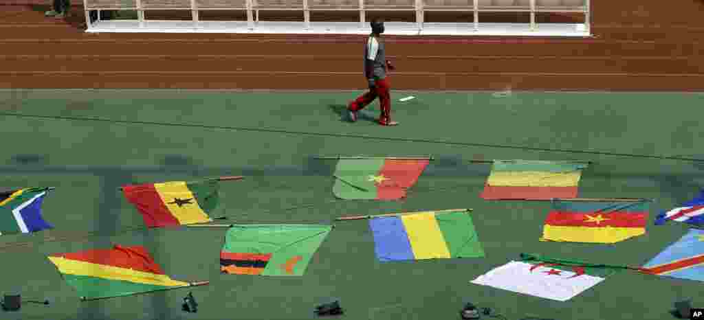Un homme passe devant les drapeaux nationaux des équipes participantes avant la cérémonie d'ouverture le premier match de footballdu Groupe A de la Coupe d'Afrique des Nations à Bata, en Guinée équatoriale, le vendredi 16 janvier 2015.