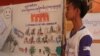 A member of the Community Youth Network stand near his artwork to raise awareness on safe migration​ at the annual reflection workshop on “Result and Role of CYN in Raising Awareness on Safe Migration and Prevention of Human Trafficking in Cambodia” on June 12, 2015, Phnom Penh. (Nov Povleakhena/VOA Khmer) 