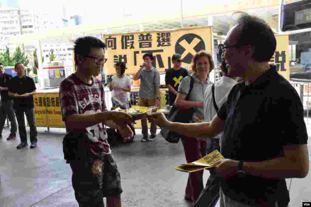 香港泛民立法會飯盒會召集人梁家傑(右)在街站向市民派發反對政改「袋住先」傳單 (美國之音湯惠芸拍攝)
