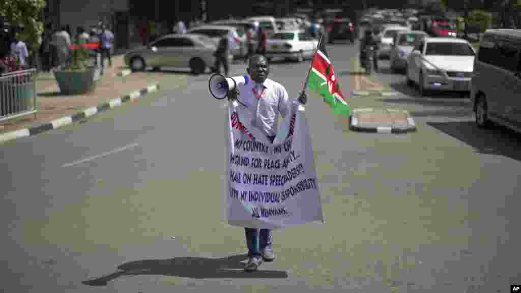 Un manifestant crie dans un mégaphone tout en tenant le drapeau du Kenya à l'extérieur du bâtiment du Parlement à Nairobi, au Kenya jeudi 18 décembre 2014.