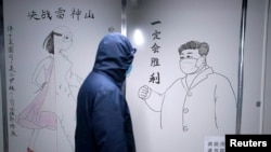 湖北省武漢市雷神山醫院一名工作人員走過中國國家主席習近平戴著口罩的素描海報。該醫院於2020年初武漢爆發Covid-19新冠疫情後火速建成。
