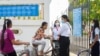 Students volunteer to take the temperature of other students and visitors entering the school ground to prevent the spread of COVID-19, in Phnom Penh, Cambodia, September 2020. (Khan Sokummono/ VOA Khmer)