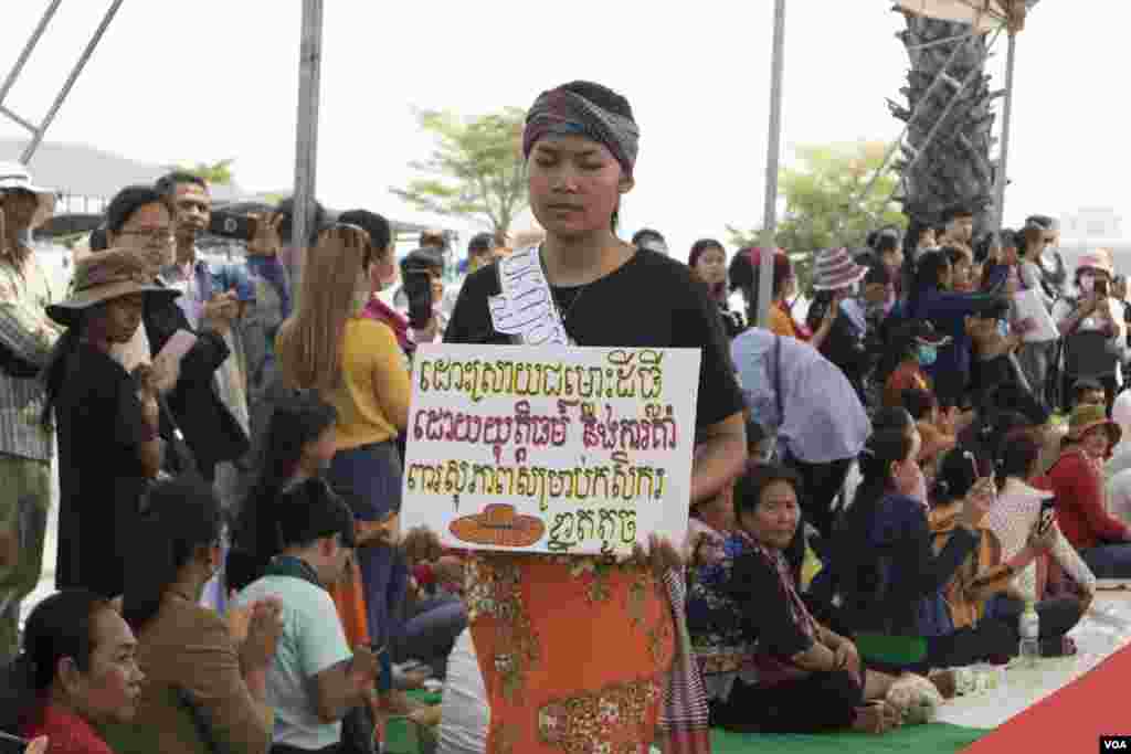 A woman performs fashion show with a slogan urging the government to resolve land disputes and to support small farmers, as groups of citizens, workers, and civil society representatives celebrate the 109th International Women Rights Day at Freedom Park in March 8, 2020. (Kann Vicheika/VOA Khmer)