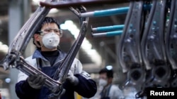 戴著口罩的工人在上海延鋒安道拓工廠汽車座椅的生產線上工作。（2020年2月24日）