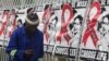 FILE - A man talks on a mobile phone as he walks past World AIDS Day banners in Johannesburg, South Africa, Dec. 1, 2014.