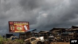 FILE - The wreckage of burnt-out car is pictured, allegedly destroyed by separatist fighters in a recent attack, as a Cameroonian soldier patrols the edge of the abandoned market in the majority anglophone Southwest province in Buea, Oct. 3, 2018. 
