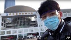 中國公民記者陳秋實在中國中部湖北省武漢市一場病毒性疫情中，在一家會議中心改建的臨時醫院前面。 (2020年2月4日)