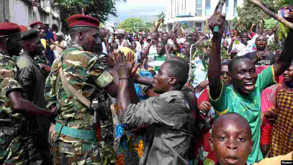 La foule salue des soldats alors qu'elle célèbre après l’annonce de la destitution du président Pierre Nkurunziza par un haut gradé de l’armée à Bujumbura, au Burundi le 13 mai 2015.